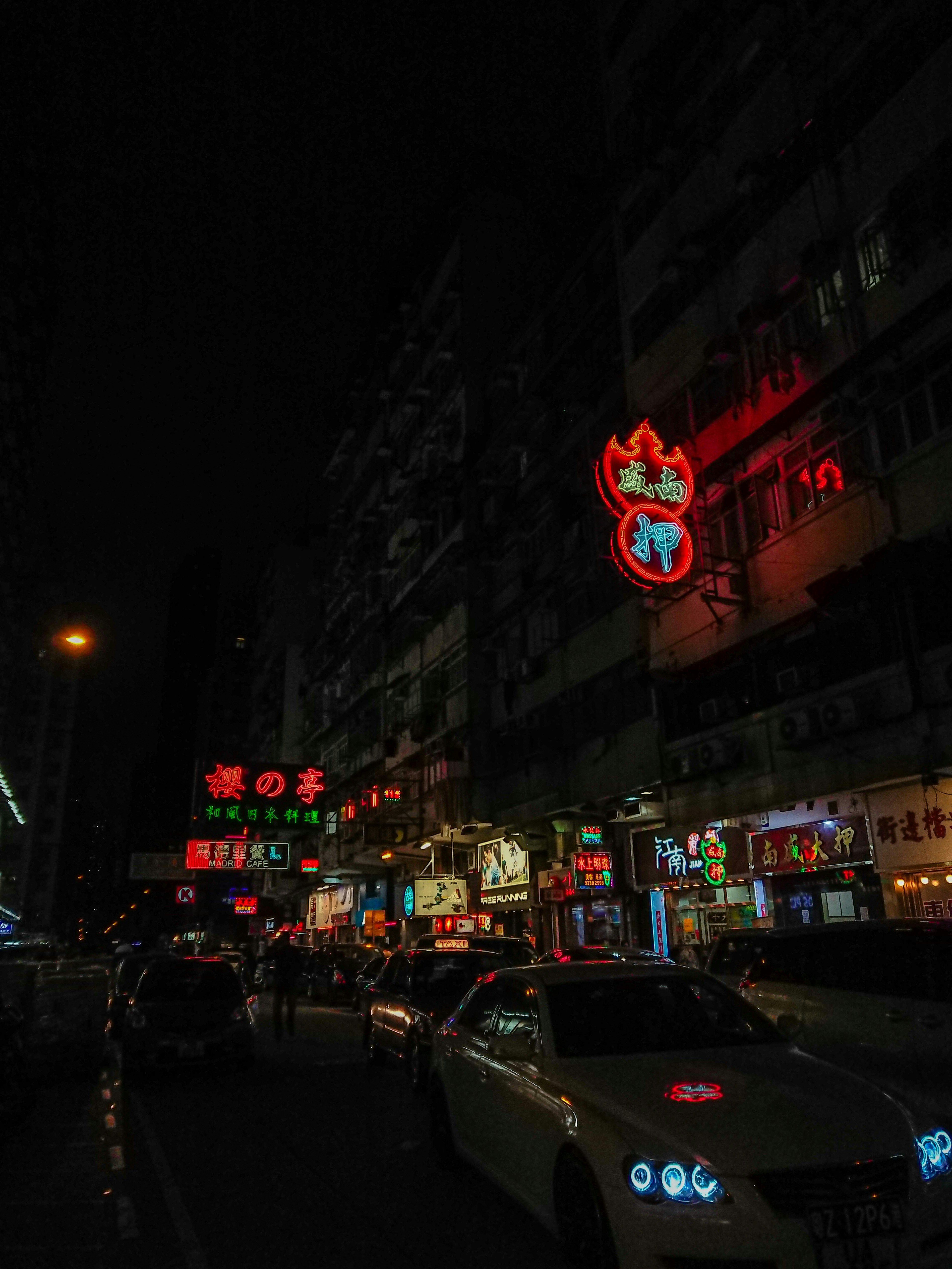 vehicles passing beside building with neon signs